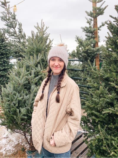 Cassie standing next to pine trees